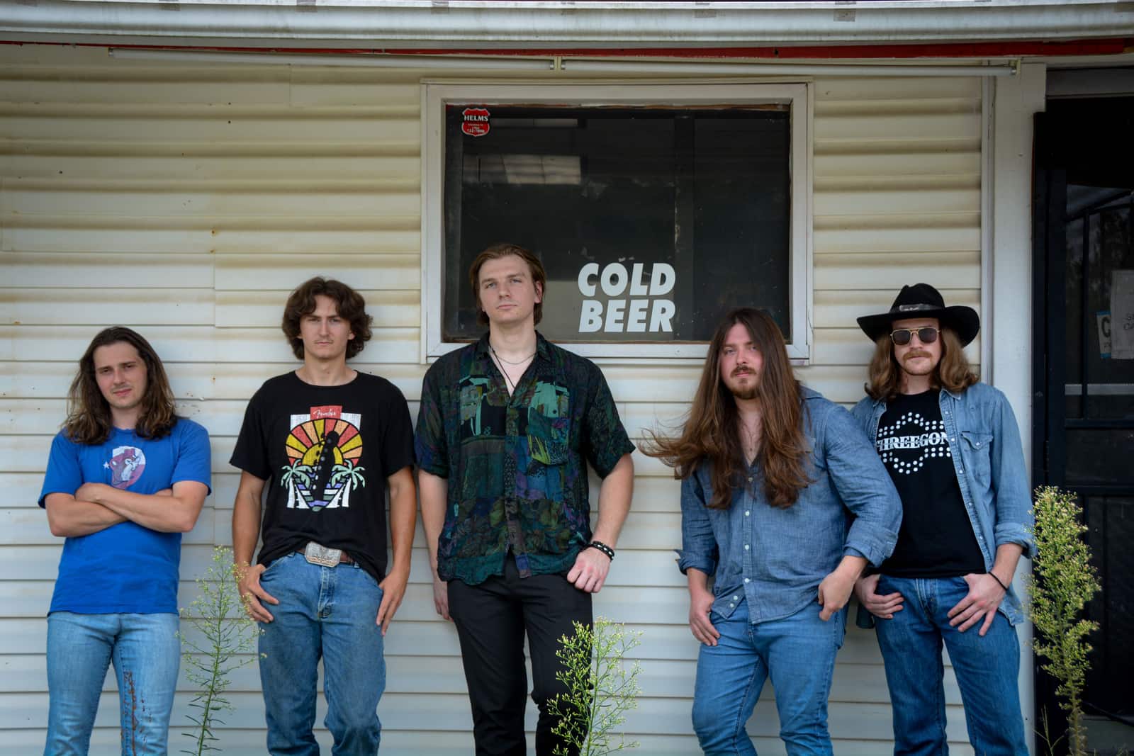 The five members of Kottonmouth lined up along the clapboard wall of a roadside bar, under a window painted COLD BEER.